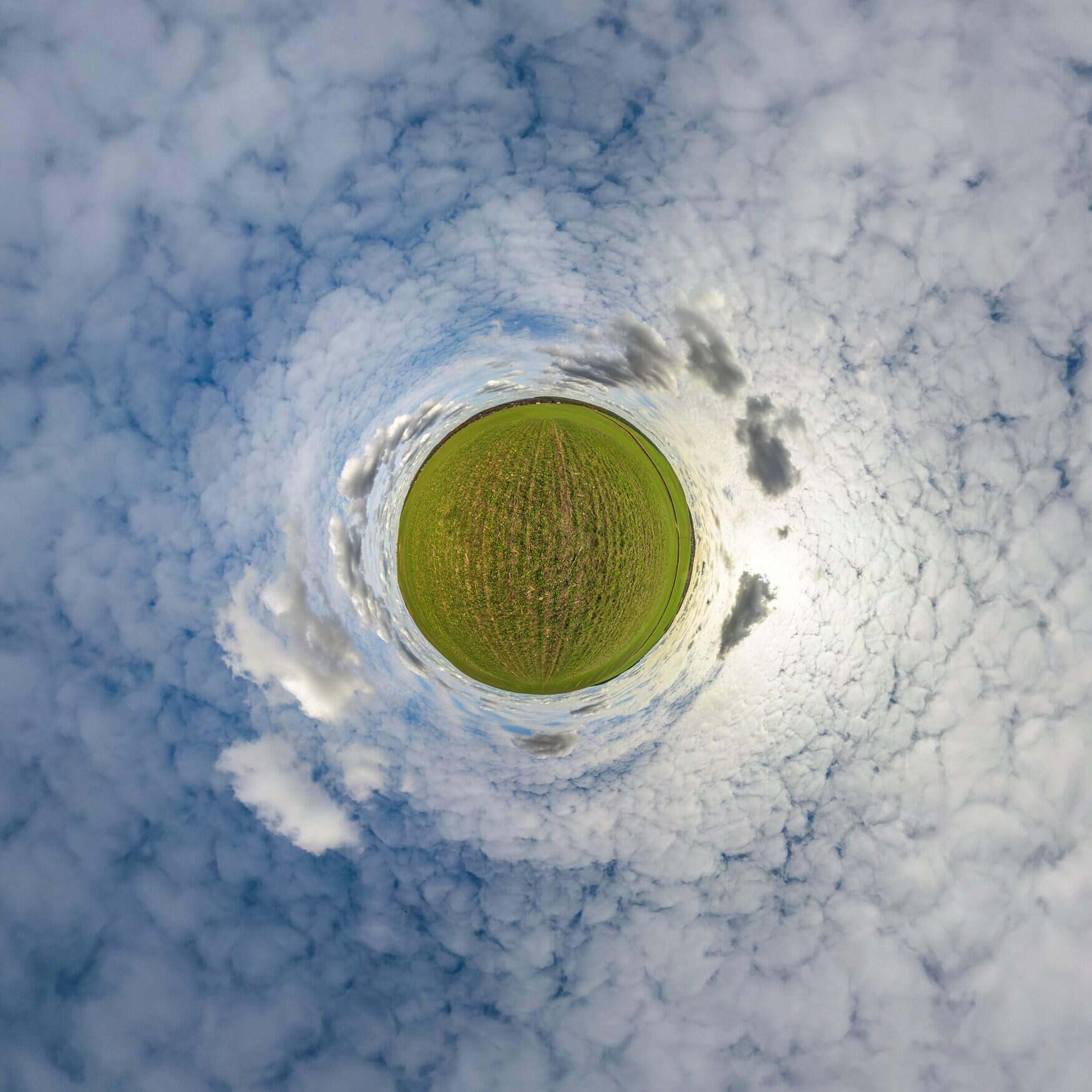 tiny planet in blue sky with beautiful clouds. Transformation of spherical panorama 360 degrees. Spherical abstract aerial view. Curvature of space.